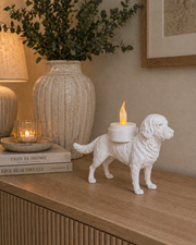 Witte Grote Münsterländer hond waxinelichthouder met led-waxinelichtje op een houten kastje langs de muur in warme huiselijke omgeving met vaas en kaarslicht.